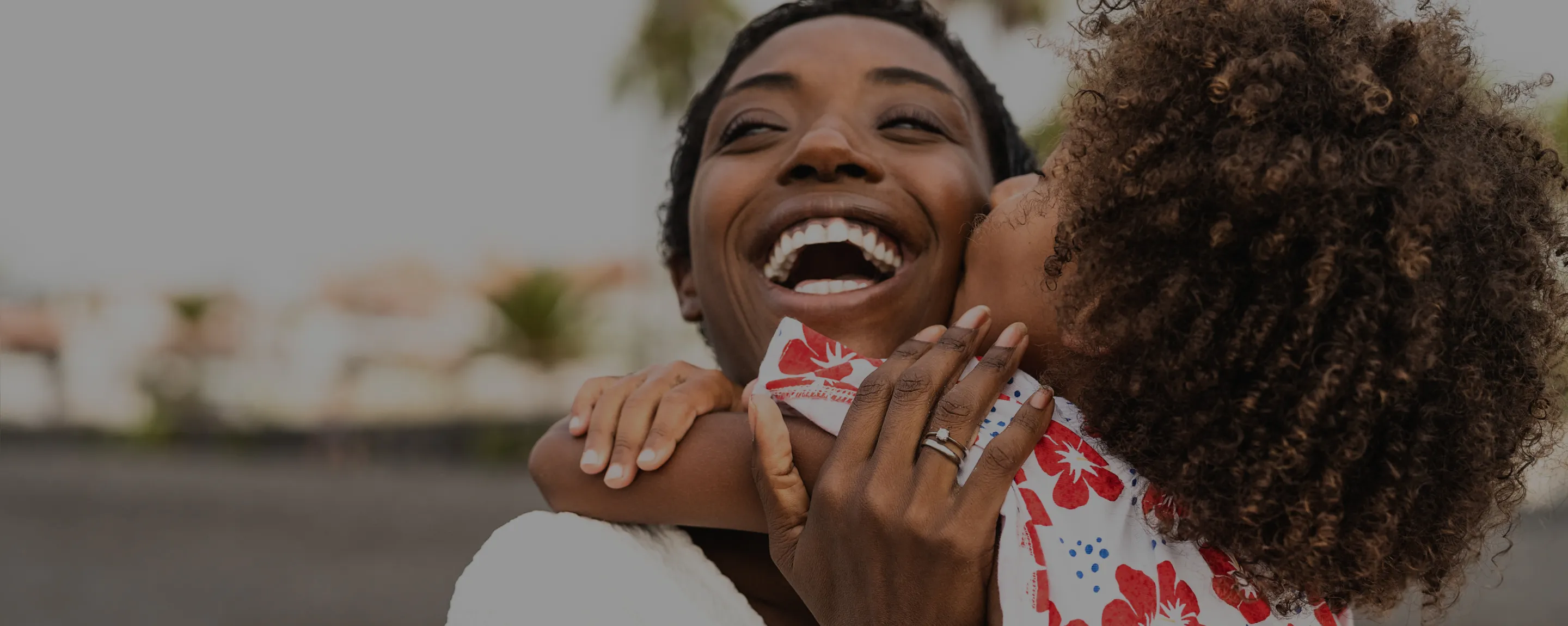 A photo of a woman and a child hugging each other with smiles.