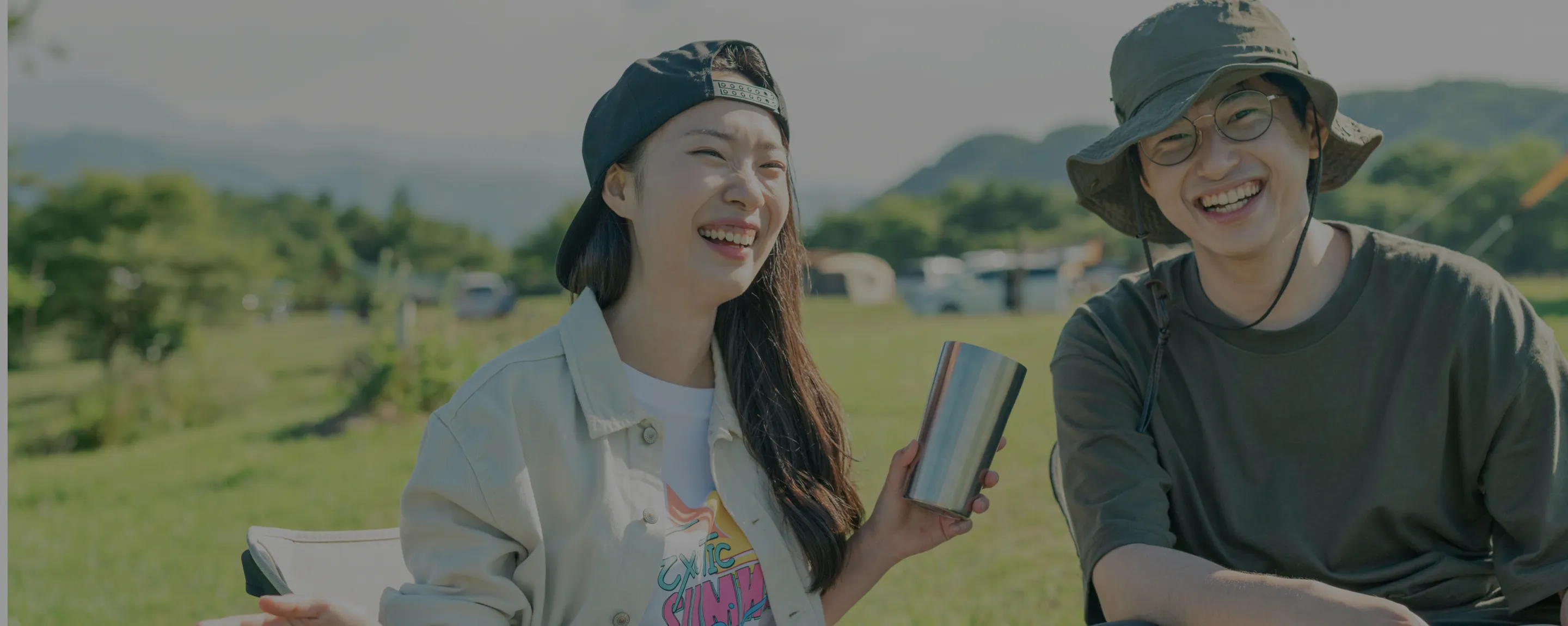 A photo of a smiling woman and man sitting in an open area in the mountains.