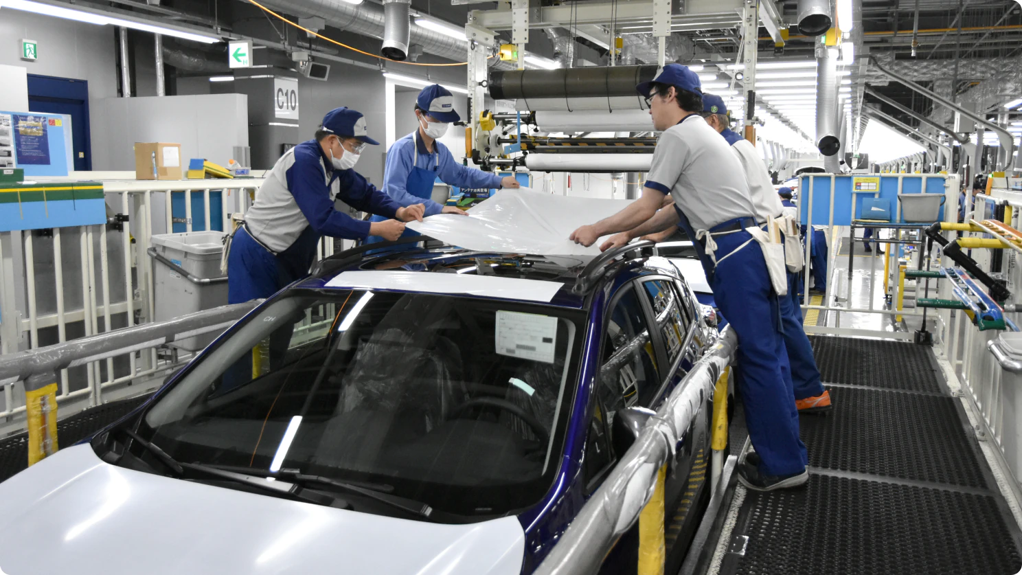 完成車両に塗膜保護フィルムを貼り付ける作業の様子